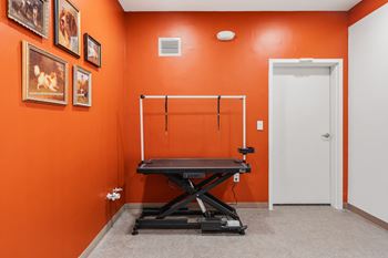 A room with orange walls has a table and a few pictures on the wall.